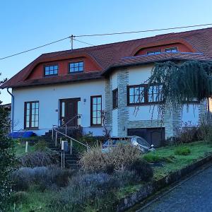 een wit huis met een rood dak bij Ferienwohnung am Zweitälerweg in Weiskirchen