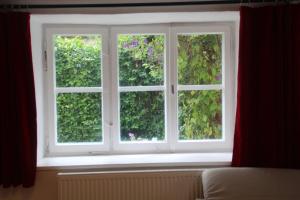 una ventana en una habitación con cortinas rojas en Charmantes Bauernhaus-Cottage 