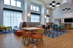 Hampton Inn & Suites Clearwater/St. Petersburg-Ulmerton Road في كليرووتر: لوبي به طاولات وكراسي وتلفزيون