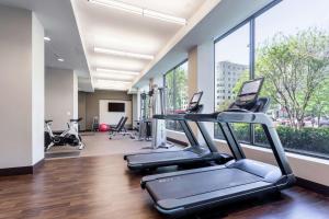 un gimnasio con cintas de correr y elípticas en una habitación con ventanas en Capital Hilton en Washington