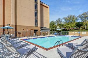 a swimming pool with chairs and a building at Hampton Inn Charlotte-Gastonia in Gastonia