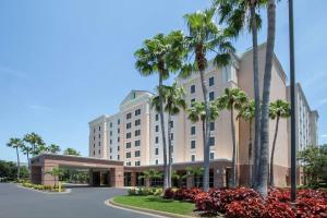 una rappresentazione dell'esterno di un hotel con palme di Embassy Suites Orlando - Airport a Orlando