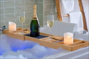 una bottiglia di champagne e due candele in una vasca da bagno di Love&Spa a Le Grau-du-Roi
