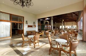 a restaurant with tables and chairs in a room at The Signature Level at Grand Palladium Imbassaí Resort & Spa in Imbassai