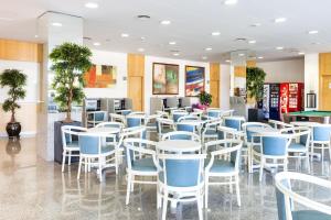 a restaurant with blue chairs and a pool table at Apartaments Condado in Lloret de Mar