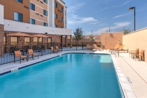 a swimming pool at a hotel with chairs and tables at Courtyard by Marriott Houston North/Shenandoah in The Woodlands
