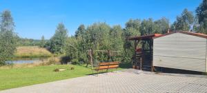 a bench sitting next to a shed next to a lake at Domek Hynka in Brodnica +2 photos