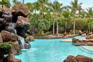 a pool with a waterfall in a resort with palm trees at Ho'olei at Grand Wailea in Wailea