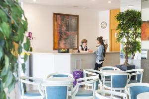 two women standing at a counter in a room with chairs at Apartaments Condado by Marsol in Lloret de Mar +17 photos