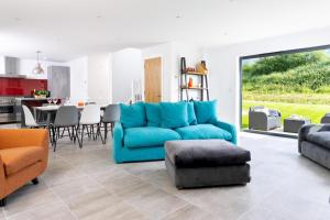 a living room with a blue couch and a kitchen at Lakeside property with spa on a nature reserve Bulrushes BV04 in Warmwell