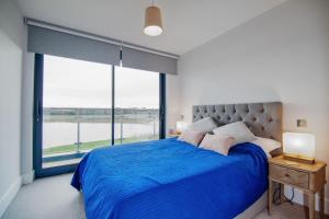 Lakeside property with spa access on a nature reserve Sandpiper BV13 في Warmwell: غرفة نوم بسرير ازرق مع نافذة كبيرة