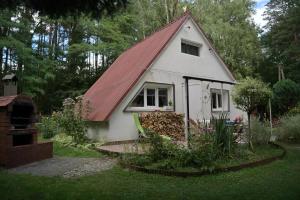 una piccola casa bianca con tetto rosso di Ostoja dom letniskowy 