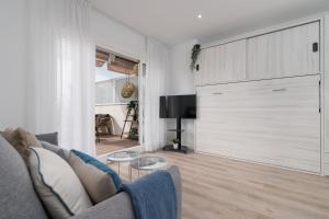 ein Wohnzimmer mit einem Sofa und einer Schiebetür in der Unterkunft Suite Homes Hesperides garden beach in Málaga