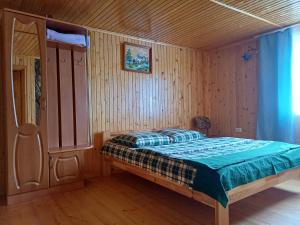 a bedroom with a bed in a wooden room at Green House Panorama Karpat in Volosyanka