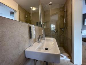 uma casa de banho com um lavatório e um chuveiro em Waldhotel Eichenhof em Aalen
