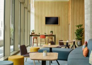 a lobby with tables and chairs and a tv on a wall at Hampton By Hilton Dublin City Centre in Dublin +38 photos