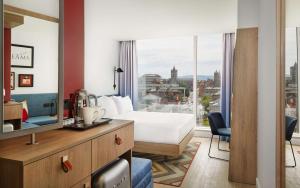 Hampton By Hilton Dublin City Centre في دبلن: غرفة فندقية بسرير ونافذة كبيرة