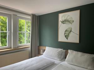 a bedroom with a bed and two windows at Waldhotel Eichenhof in Aalen