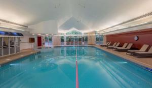 a large swimming pool in a hotel with chairs around it at Hilton Leicester Hotel in Leicester