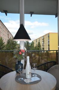 a table with two glasses and a bottle and a lamp at Apartment Hemsen in Prešov