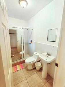 a white bathroom with a toilet and a sink at Hotel Cabañas River Park in Omoa