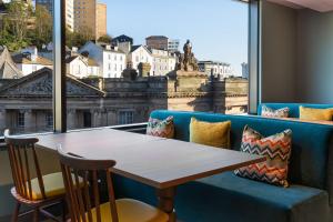 a table and chairs in a room with a large window at Hampton By Hilton Torquay in Torquay