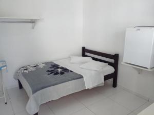 uma pequena cama num quarto branco com em HOTEL MORADA DO SOL em Pontal do Paraná