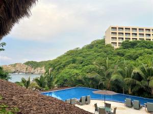 a resort swimming pool with chairs and a building at Coral Blue Huatulco in Santa Cruz Huatulco