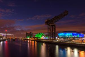 una grande gru accanto a un fiume di notte di Hilton Garden Inn Glasgow City Centre a Glasgow