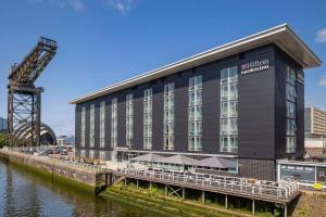 um grande edifício ao lado de uma massa de água em Hilton Garden Inn Glasgow City Centre em Glasgow