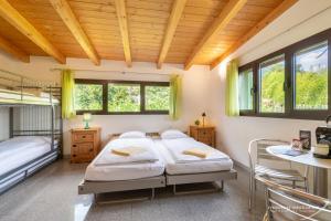 2 Betten in einem Zimmer mit Holzdecken und Fenstern in der Unterkunft Bamboohouse Motel Riazzino in Riazzino