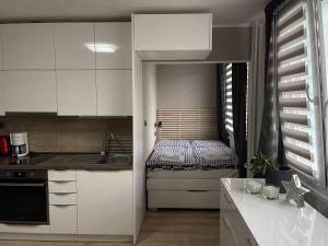 a kitchen with white cabinets and a small bed at Studio Prosek in Prague