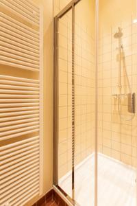 a shower with a glass door in a bathroom at Pauline Loveling apartment with quiet garden and 2 bathrooms in Antwerp
