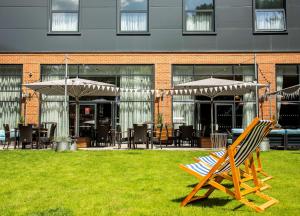 a couple of chairs and umbrellas in a yard at Hilton Garden Inn Abingdon Oxford in Abingdon