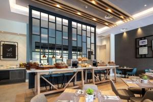 a restaurant with a large window and tables and chairs at Hilton Garden Inn Abingdon Oxford in Abingdon
