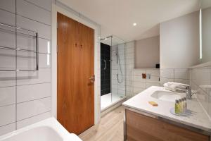 y baño con lavabo, bañera y ducha. en Hilton Garden Inn Abingdon Oxford, en Abingdon