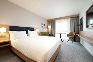 a hotel room with a large bed and a desk at Hilton Garden Inn Abingdon Oxford in Abingdon