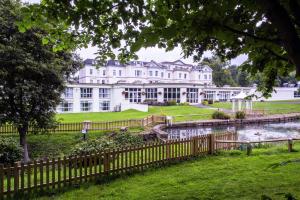 切尔滕纳姆DoubleTree by Hilton Cheltenham-Cotswolds的水域旁边的一座白色大楼