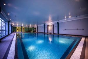 a large swimming pool with blue water in a building at DoubleTree by Hilton Cheltenham in Cheltenham