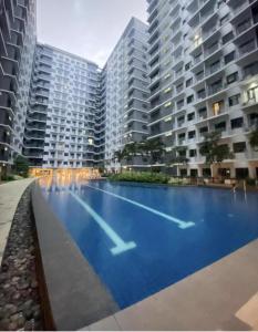 a large swimming pool in front of two tall buildings at MOA Pasay, Shore 3 Residences - Modern Luxury Condo in Manila