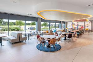 a restaurant with tables and chairs and windows at Hampton by Hilton High Wycombe in High Wycombe