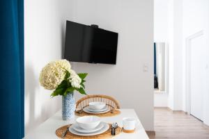 une table à manger avec un vase de fleurs et une télévision dans l'établissement Apartamenty Emilia, à Gniezno