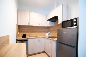 Apartamenty Emilia في غنيزنو: مطبخ فيه دواليب بيضاء وثلاجة سوداء
