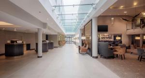 a lobby with chairs and tables in a building at DoubleTree by Hilton London Heathrow Airport in Hillingdon