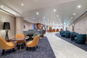 a lobby with chairs and tables and a waiting room at Hilton Garden Inn London Heathrow Terminal 2 and 3 in Hillingdon