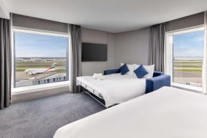 a hotel room with two beds and a large window at Hilton Garden Inn London Heathrow Terminal 2 and 3 in Hillingdon