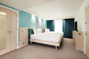 a bedroom with a large white bed and a television at Hampton By Hilton London Docklands in London