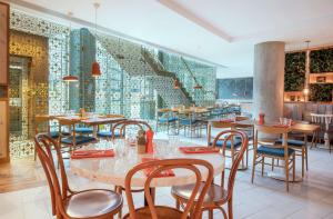 ロンドンにあるLincoln Plaza Hotel London, Curio Collection By Hiltonの木製のテーブルと椅子、壁画のあるレストラン