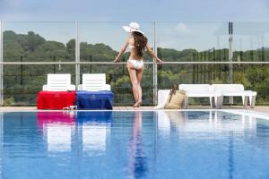 a woman in a bikini standing next to a swimming pool at Apartaments Condado by Marsol in Lloret de Mar