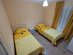 2 camas en una habitación pequeña con sábanas amarillas en Sunshine Inn Buriani, en Buriaki